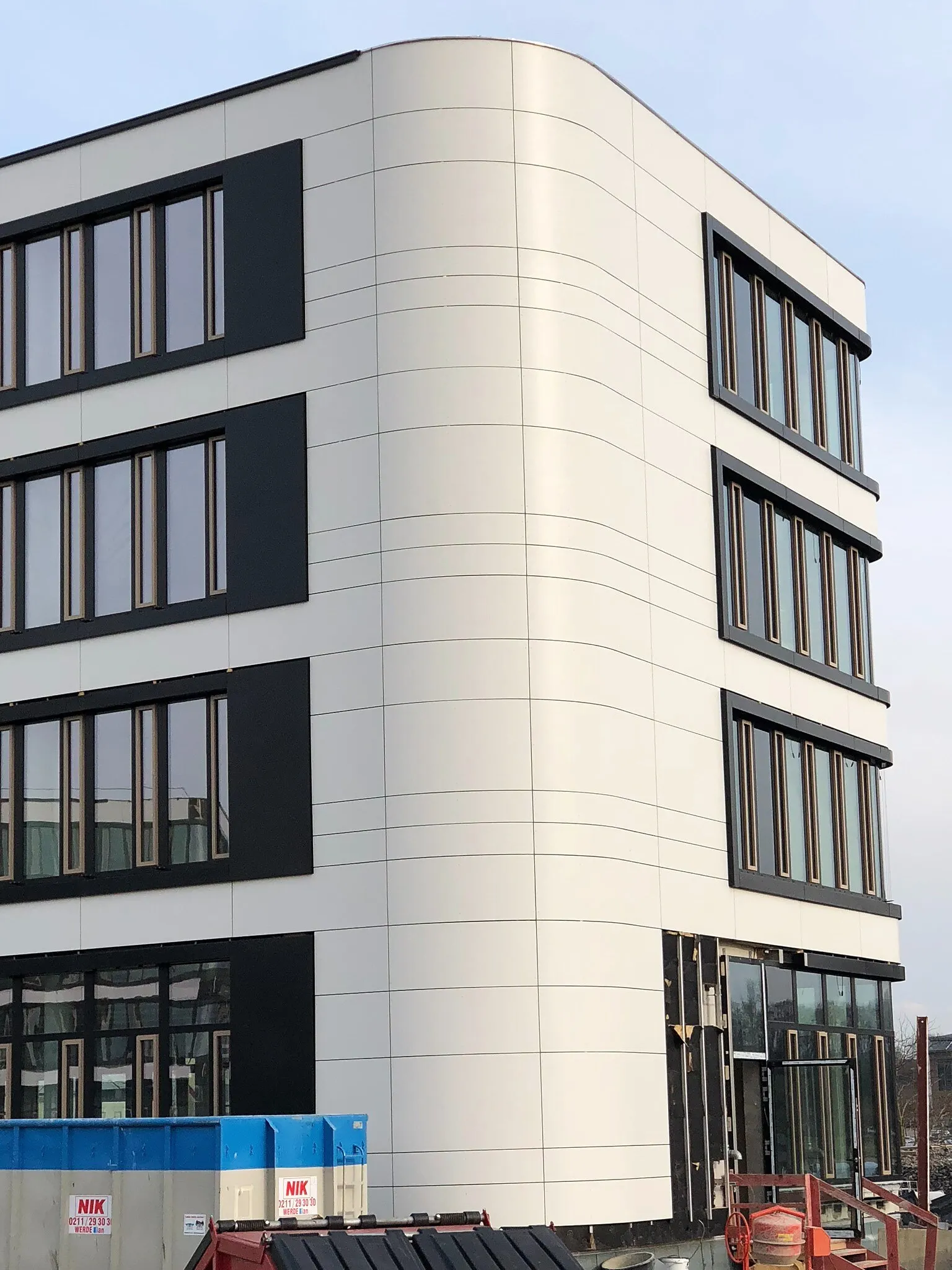 Verwaltungsgebäude von Amprion in Dortmund mit gerundeter Gebäudeecke, hellen Fassadenplatten und dunklen Fensterrahmungen