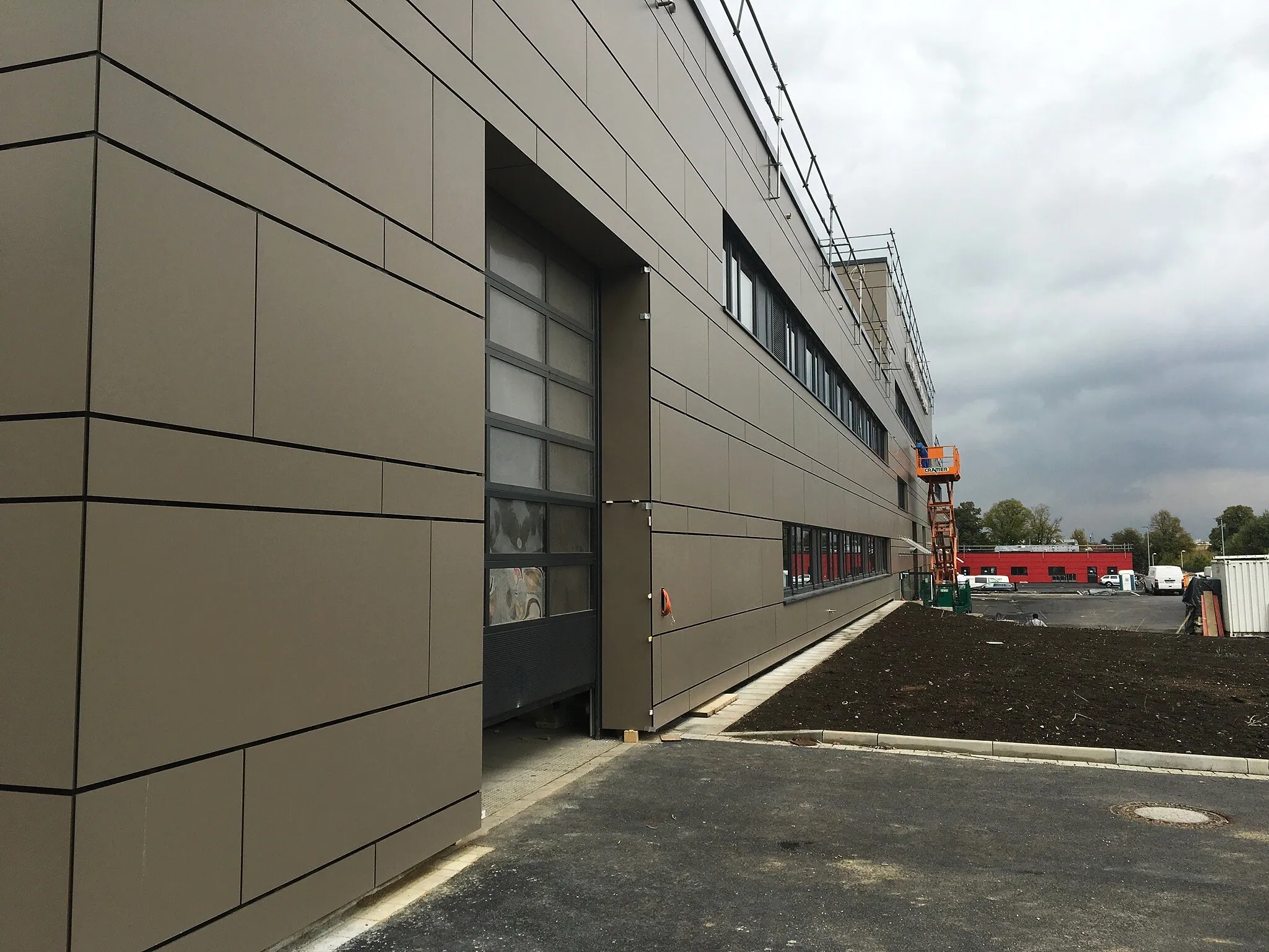 Feuerwehrgebäude in Frechen mit großformatigen graubraunen Fassadenplatten und einem Hallentor mit Glasfeldern