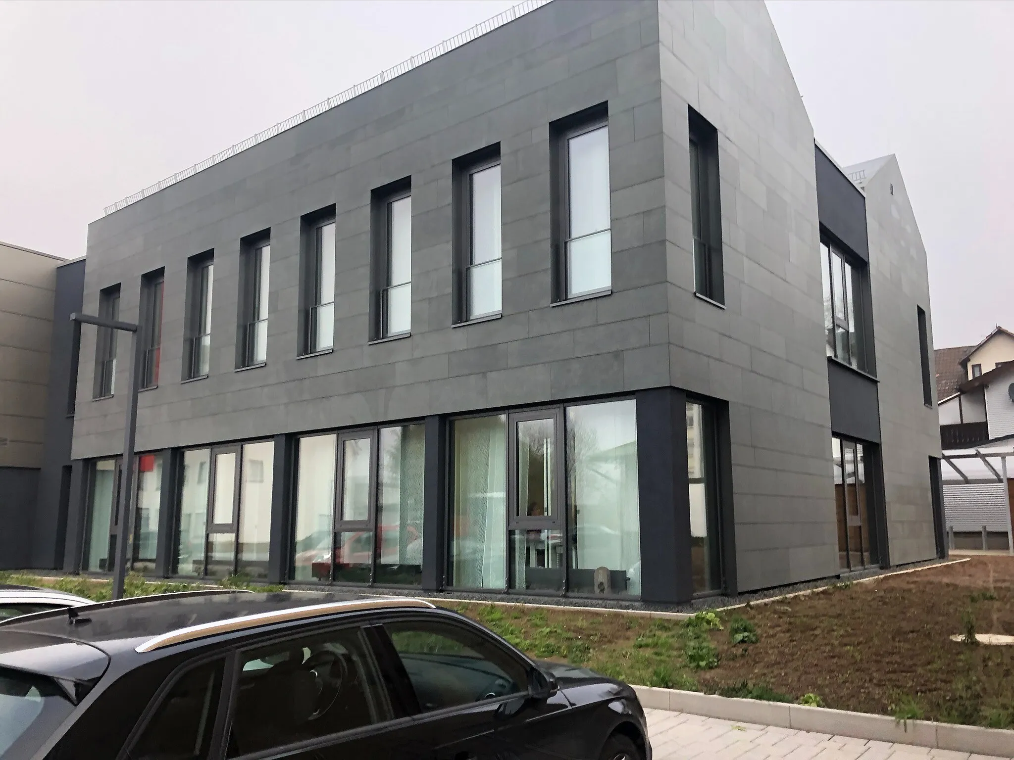 Gebäude der Sparkasse in Marburg mit anthrazitfarbener Plattenfassade und verglastem Erdgeschoss